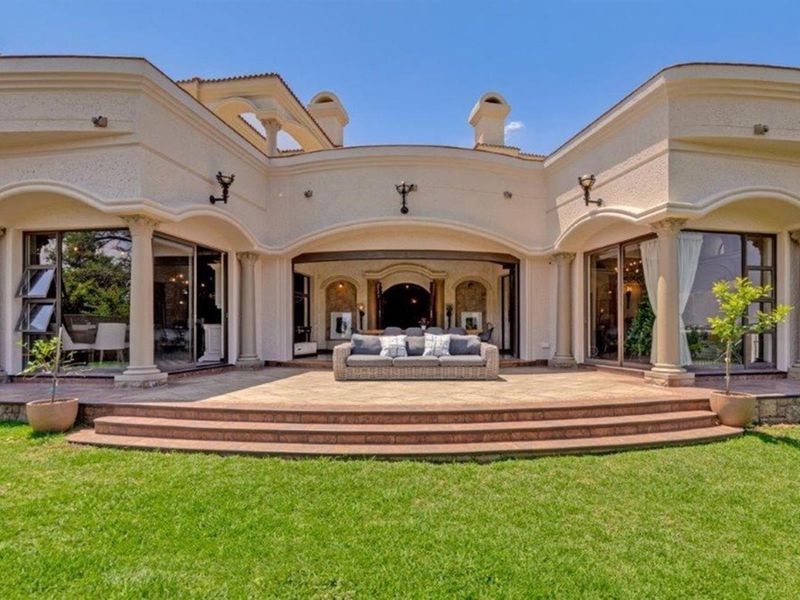 A spacious rear patio featuring stone tiling, decorative columns, and arched architectural elements, providing a seamless transition between the indoor living areas and the garden.