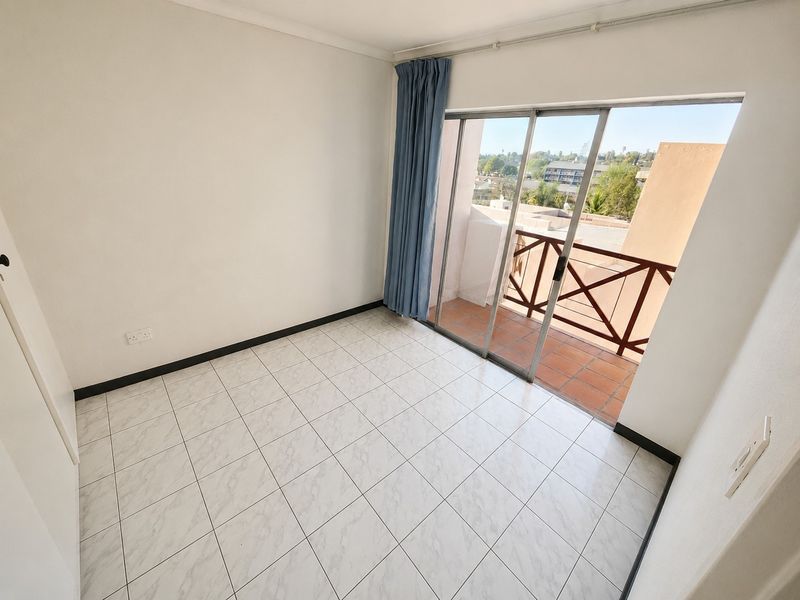 An empty bedroom featuring tiled flooring and a sliding glass door that provides direct access to a private balcony.