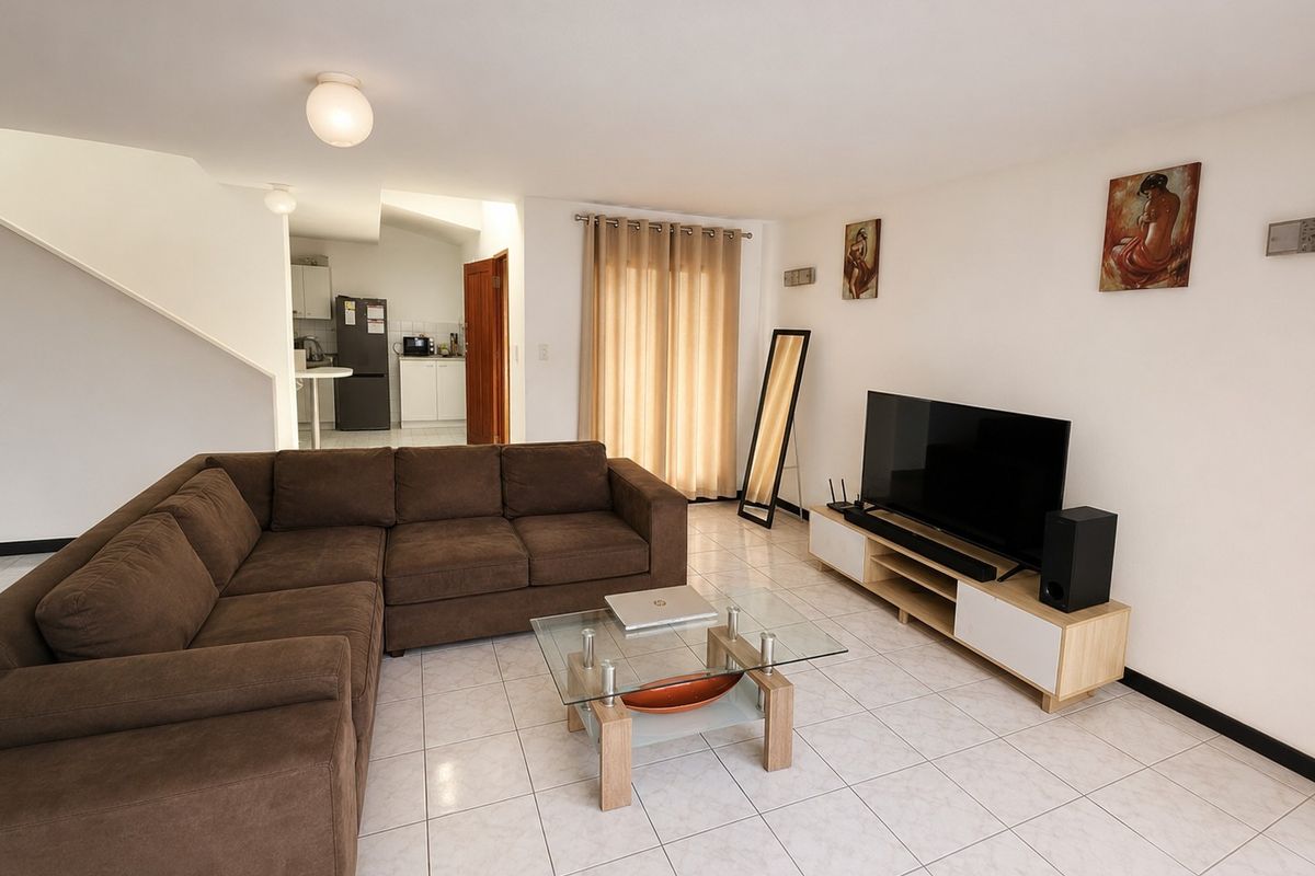 Open plan living area featuring tiled flooring and a staircase, with a view into the adjacent kitchen space.
