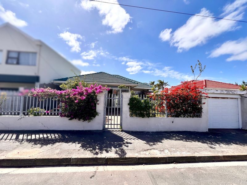 Front elevation of a residential property featuring a perimeter wall, metal gate, and integrated garage, set behind a street-facing boundary.
