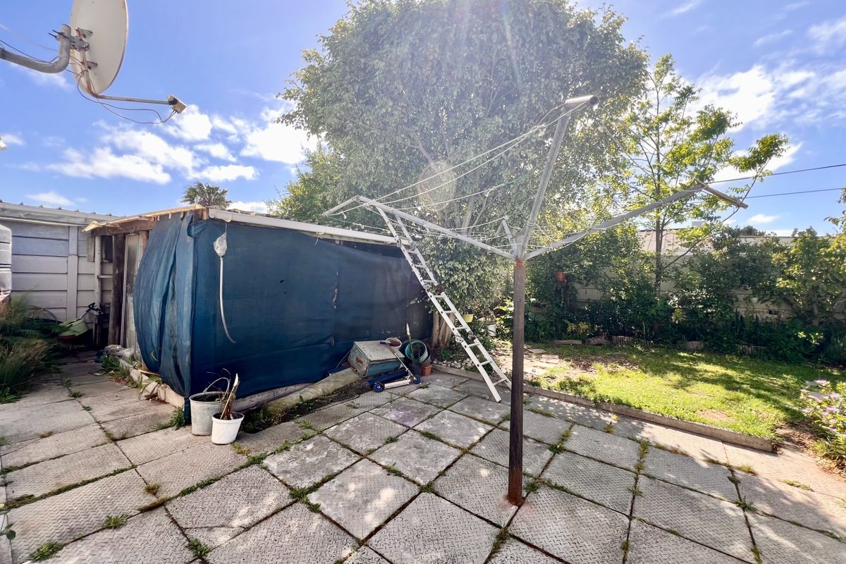 Rear garden area featuring a paved patio, rotary clothesline, and a basic storage shed structure.