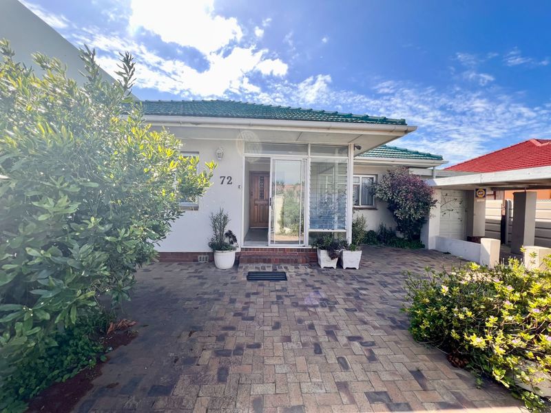 Front elevation of a single-story residence featuring a paved driveway, tiled roof, and a covered entrance with a timber front door.