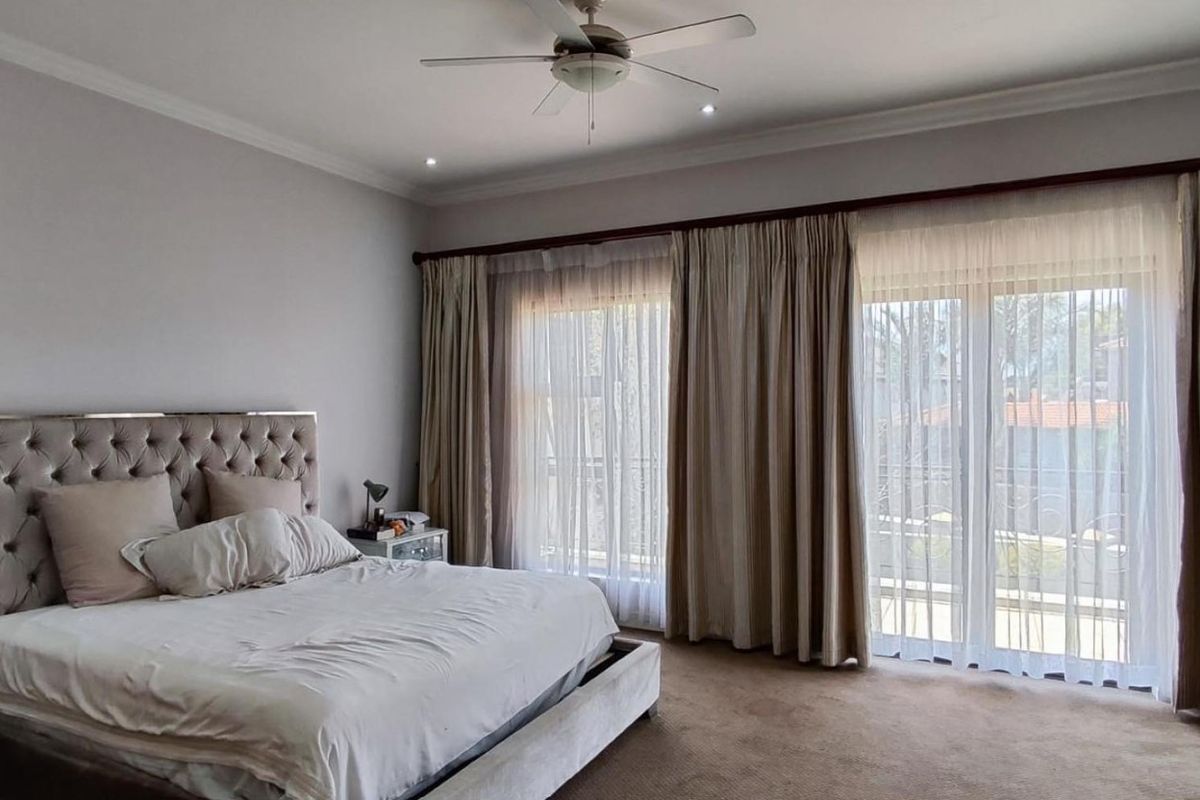 Spacious bedroom featuring carpet flooring, recessed lighting, a ceiling fan, and large sliding glass doors that provide ample natural light.
