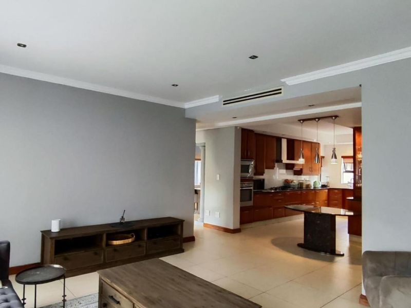 Spacious open-plan living area featuring tiled floors, recessed lighting, and a well-appointed kitchen with built-in cabinetry and integrated appliances.