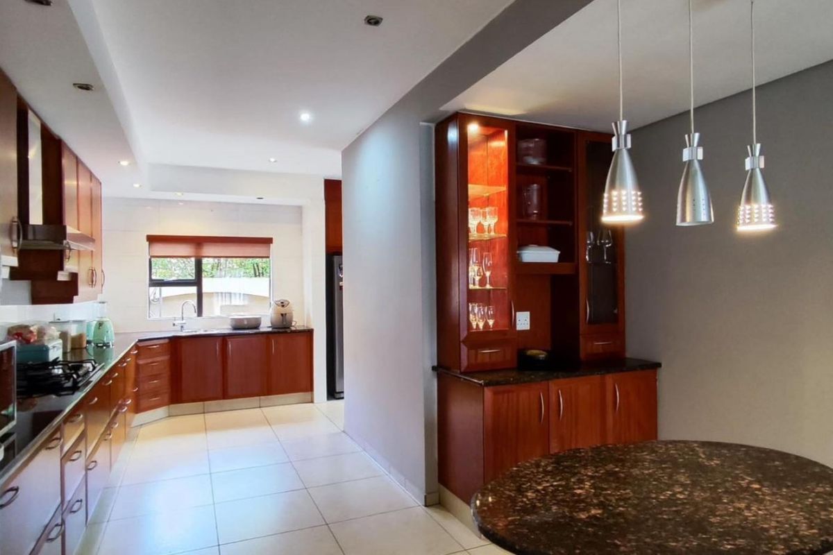 Spacious kitchen featuring warm wood cabinetry, granite countertops, built-in appliances, and a dedicated dining nook with elegant pendant lighting.