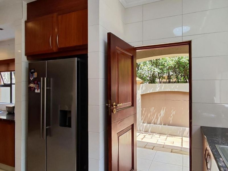 A functional kitchen featuring wood cabinetry, granite countertops, and direct access to an outdoor patio area.