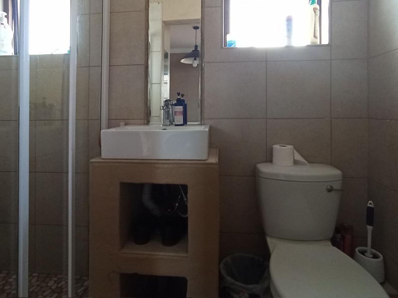 A functional bathroom featuring a tiled shower enclosure, a vessel sink with an open vanity base, and a standard toilet.