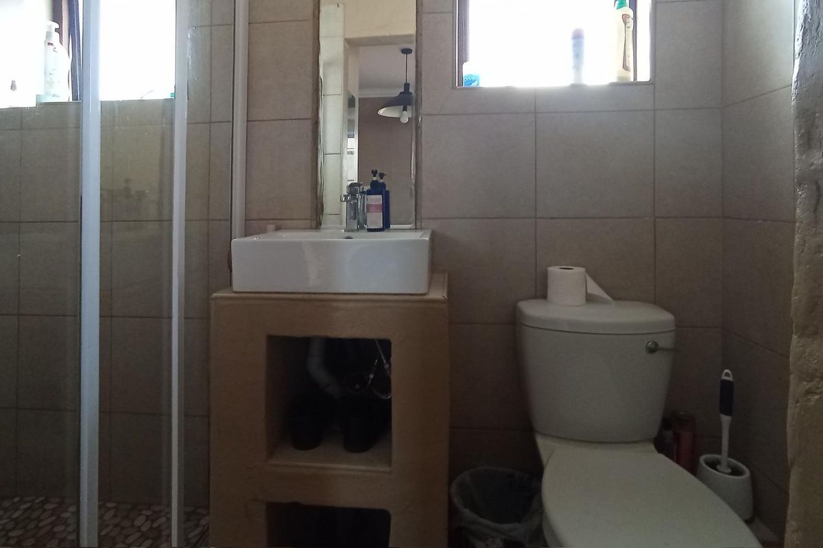 A functional bathroom featuring a tiled shower enclosure, a vessel sink with an open vanity base, and a standard toilet.