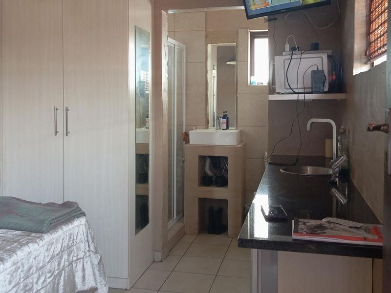 Compact open-plan studio space featuring a kitchenette with granite countertops, a built-in wardrobe, and an en-suite bathroom with a shower.