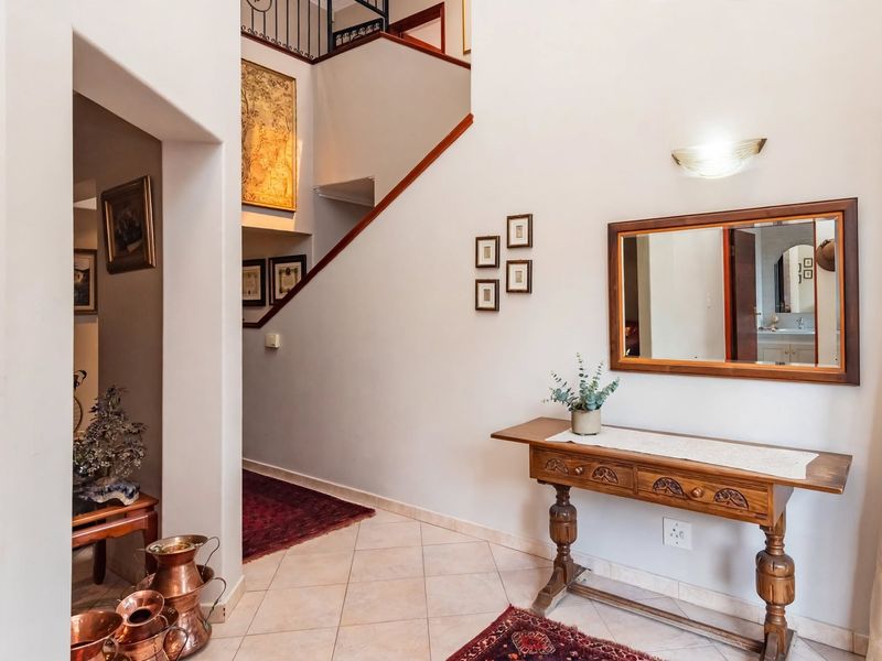 A welcoming entrance hall featuring tiled flooring, a staircase with a wrought iron balustrade, and a wall-mounted light fixture.