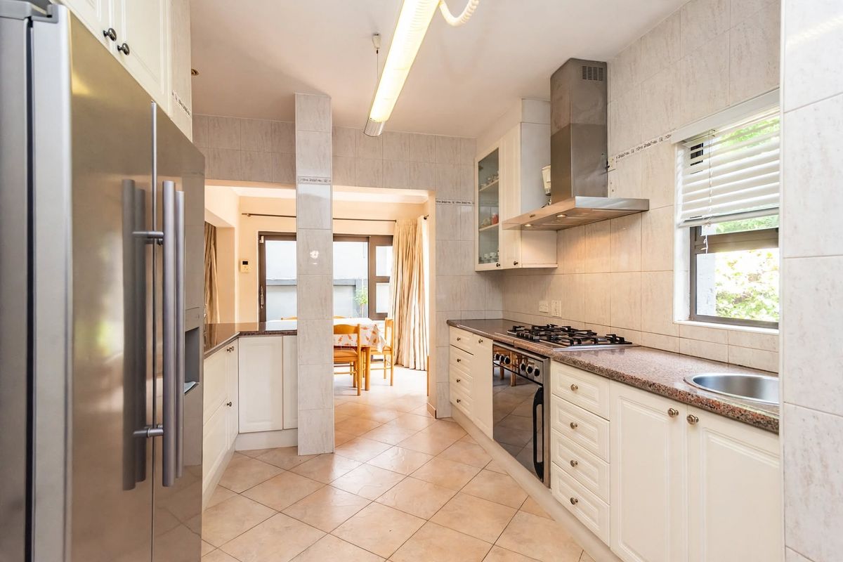 Functional kitchen featuring granite countertops, built-in cabinetry, stainless steel gas hob, extractor fan, and tiled finishes, with an adjacent dining area.