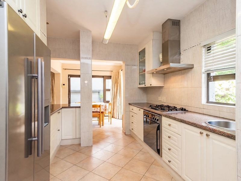Functional kitchen featuring granite countertops, built-in cabinetry, stainless steel gas hob, extractor fan, and tiled finishes, with an adjacent dining area.