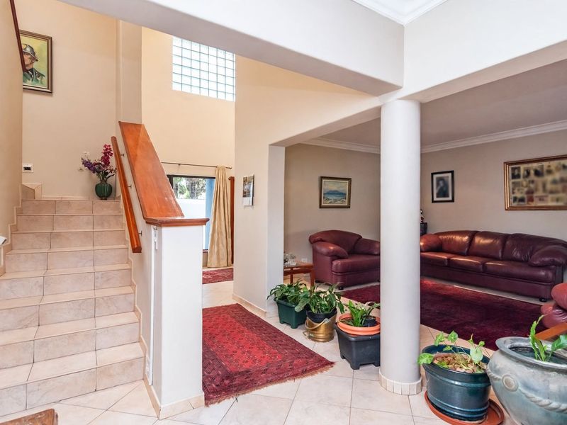Entrance foyer featuring a tiled staircase with a wooden handrail, leading into an open-plan living area with a prominent structural column.