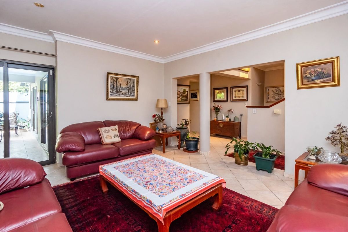 Spacious living room featuring ceramic tile flooring, recessed lighting, decorative crown molding, and a sliding glass door providing access to the patio area.