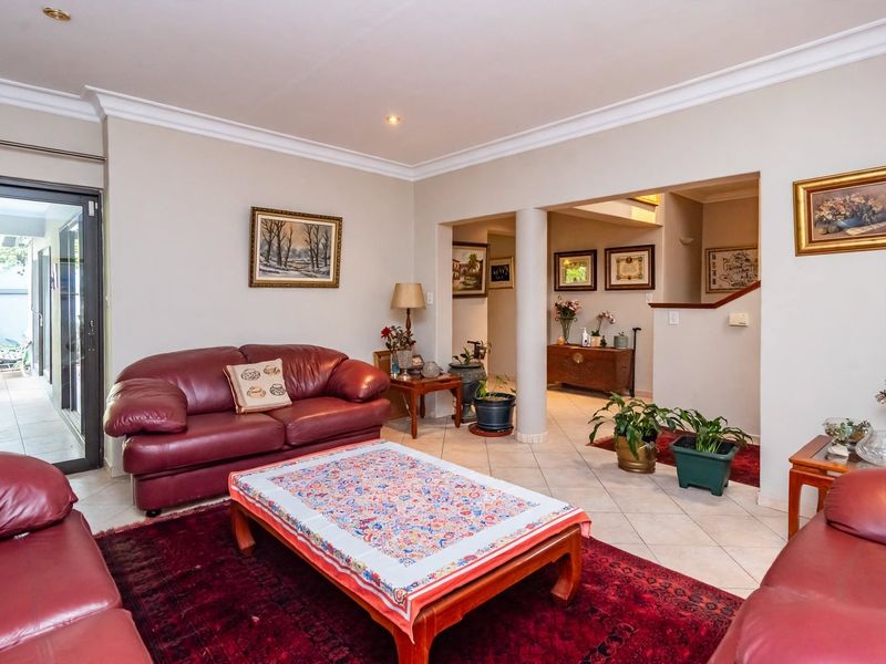 Spacious living room featuring ceramic tile flooring, recessed lighting, decorative crown molding, and a sliding glass door providing access to the patio area.
