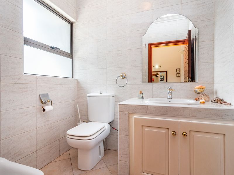 A functional bathroom featuring tiled walls and flooring, a vanity cabinet with a basin, and a wall-mounted mirror.