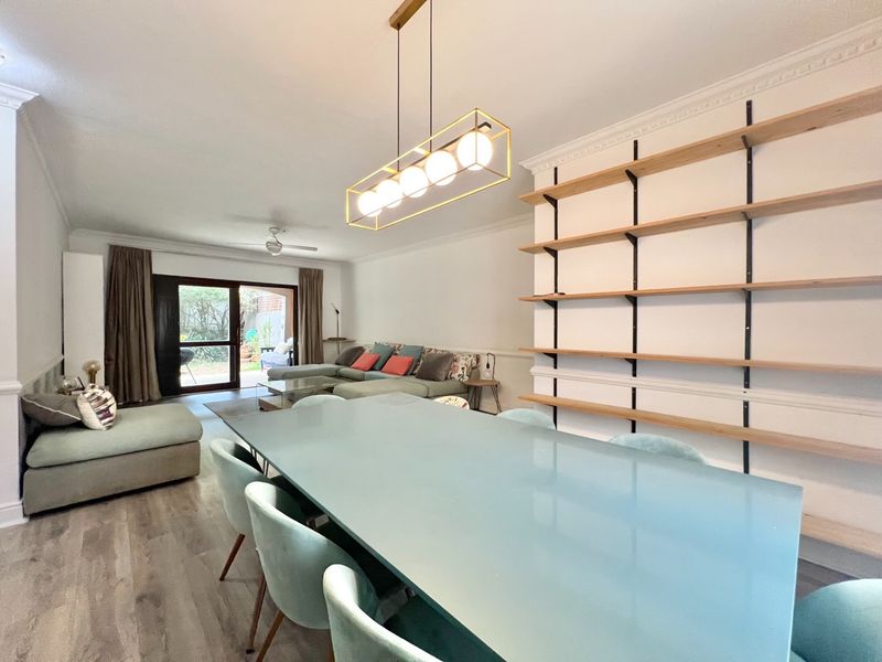 Spacious open-plan living and dining area featuring built-in wall shelving, crown molding, and direct access to an outdoor patio through sliding glass doors.