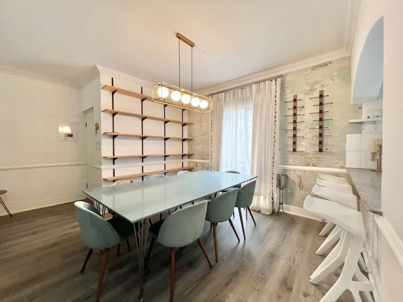 Dining area featuring built-in shelving, laminate flooring, and a breakfast bar, requiring cosmetic attention to the wall finishes.