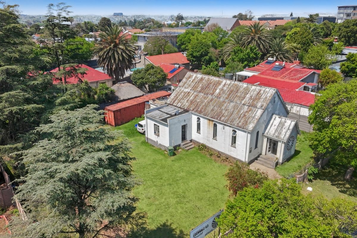 Aerial view of a commercial property featuring a building with a corrugated metal roof and masonry exterior, situated on a landscaped lot.