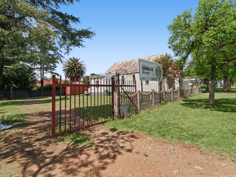 Front view of a commercial property featuring a gated entrance, perimeter fencing, and a corrugated metal roof structure.