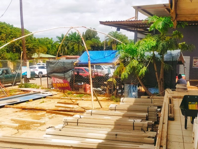 An outdoor area showing a tiled patio section adjacent to an unpaved yard with various construction materials and temporary structures.