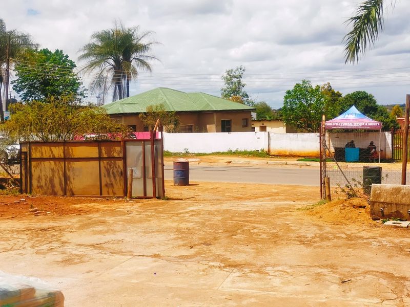 Exterior view of the property frontage featuring a concrete driveway, perimeter wall, and gated access point.