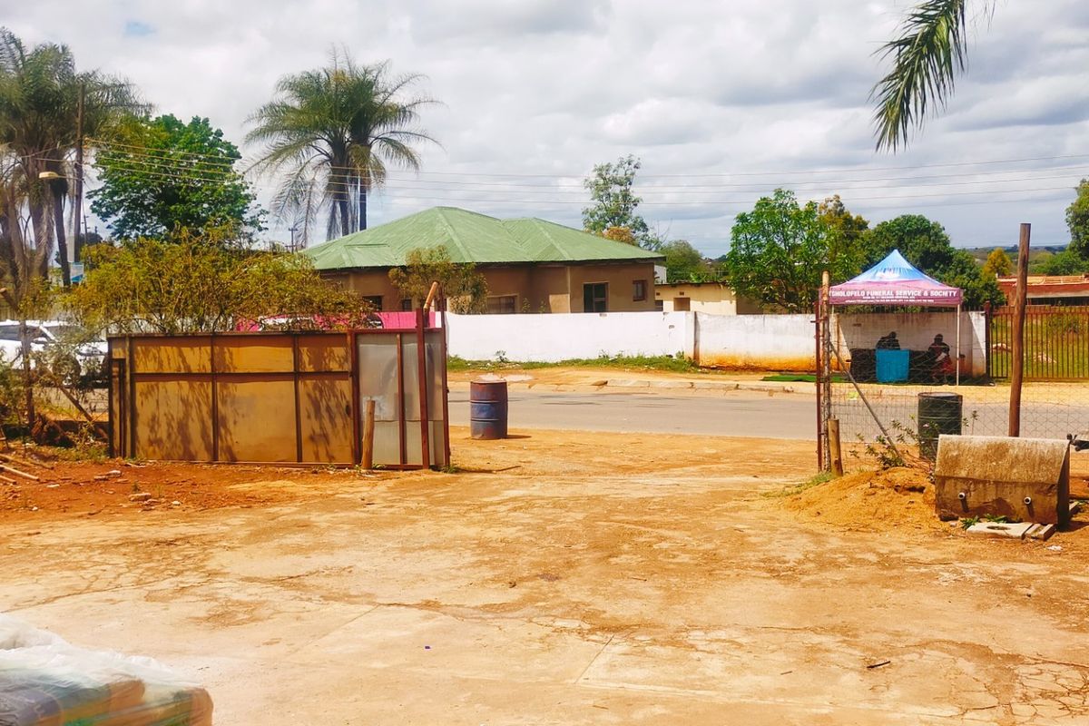 Exterior view of the property frontage featuring a concrete driveway, perimeter wall, and gated access point.