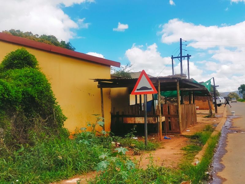 Street view showing a roadside commercial structure with adjacent unpaved verge and overhead utility infrastructure.