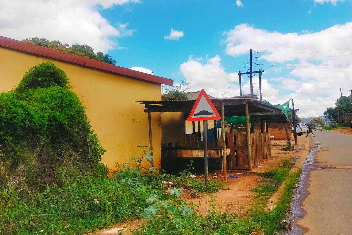 Street view showing a roadside commercial structure with adjacent unpaved verge and overhead utility infrastructure.