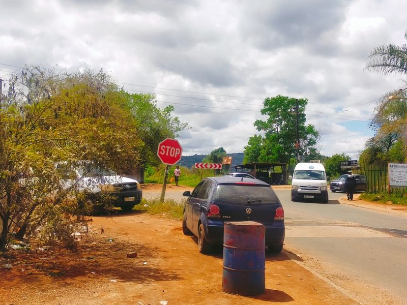 A street-level view showing the road approach, surrounding vegetation, and local traffic infrastructure near the property entrance.