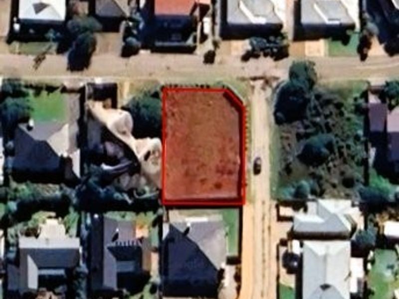 An aerial view of a vacant residential plot of land situated within an established suburban neighborhood.