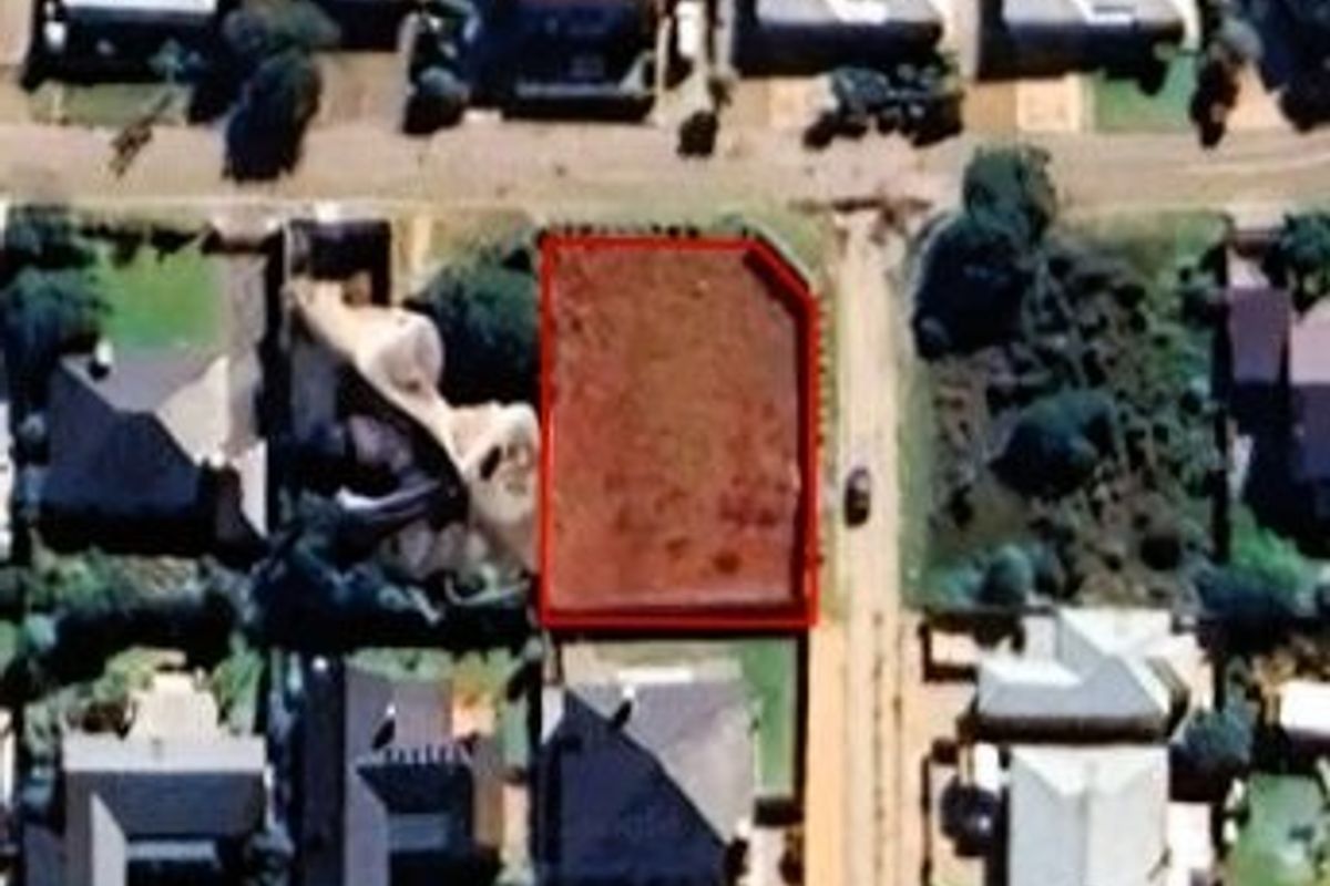An aerial view of a vacant residential plot of land situated within an established suburban neighborhood.