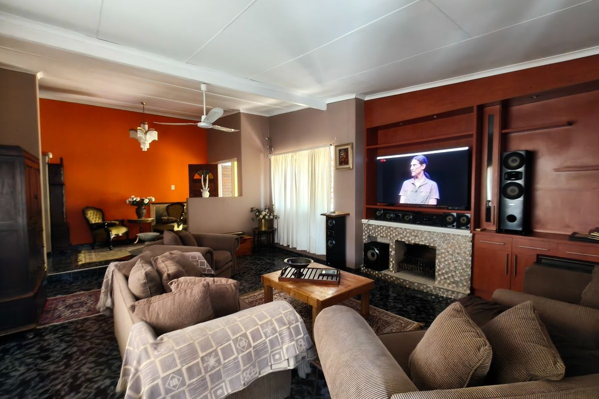 Spacious living room featuring a stone-clad fireplace, extensive built-in wooden cabinetry, and tiled flooring, offering a comfortable and functional family entertainment area.