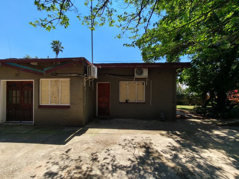 Rear exterior view of the property featuring timber cladding, concrete patio area, and dual split system air conditioning units.