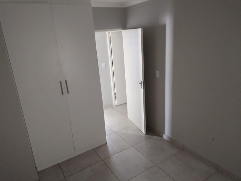 A clean, empty bedroom featuring neutral tiled flooring and a built-in wardrobe, offering a blank canvas for personalization.