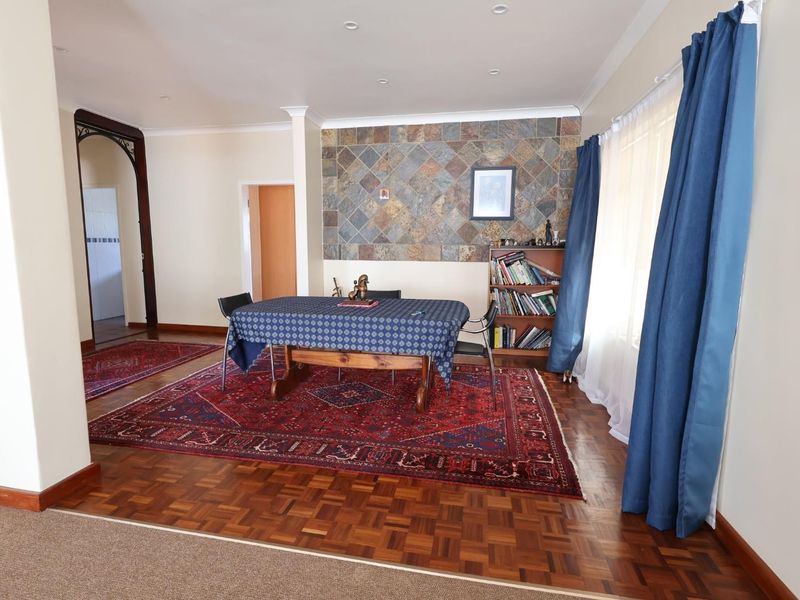 Spacious dining area featuring classic parquet flooring, a decorative stone feature wall, and recessed lighting, creating a warm and inviting atmosphere.