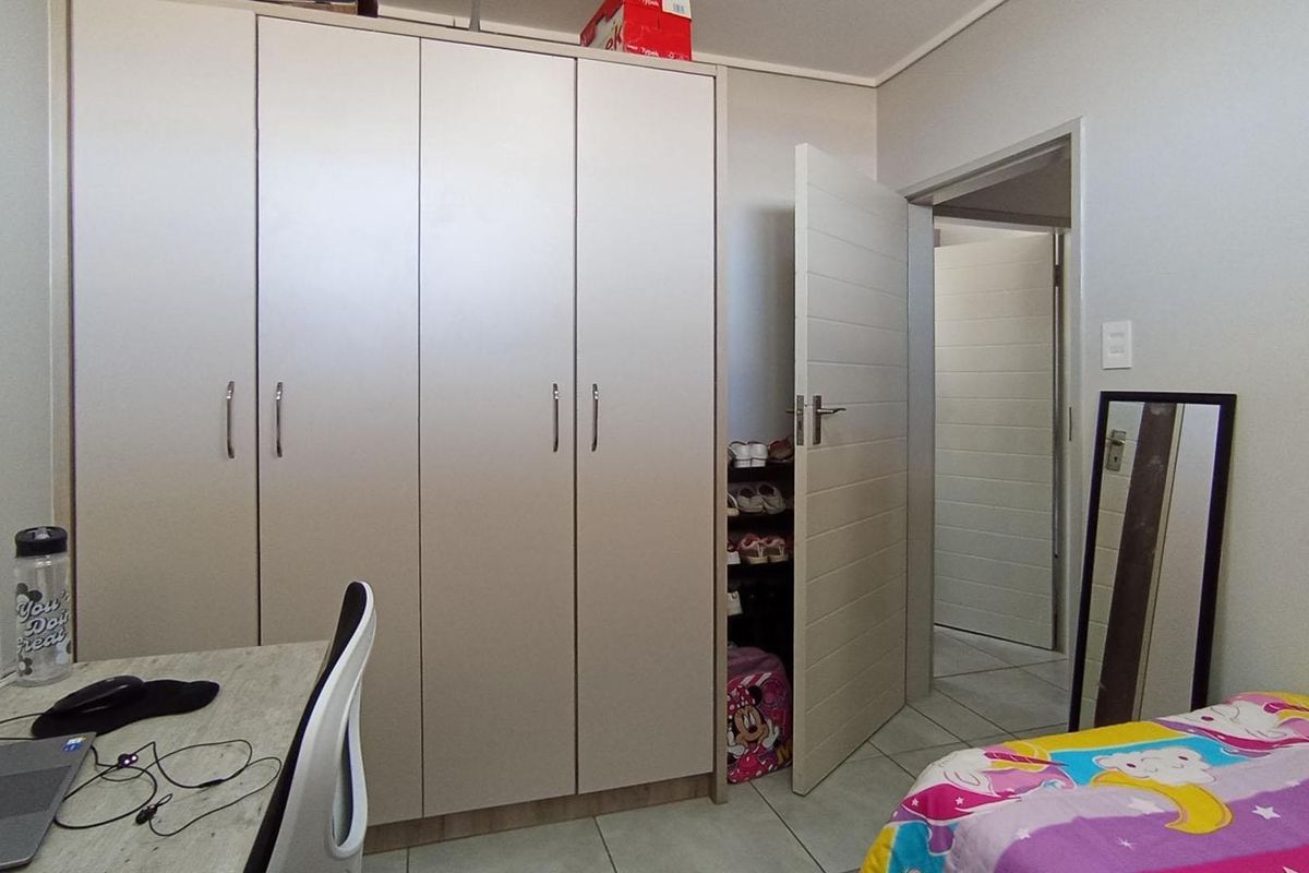 A functional bedroom featuring built-in cupboards, tiled flooring, and a neutral interior finish.