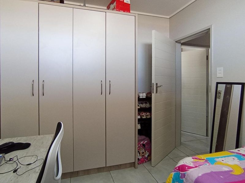 A functional bedroom featuring built-in cupboards, tiled flooring, and a neutral interior finish.
