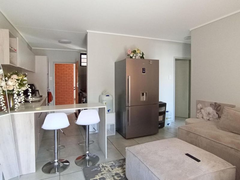 Open-plan living area featuring a modern kitchen with breakfast bar, tiled flooring, and neutral wall finishes, creating a functional and cohesive living space.