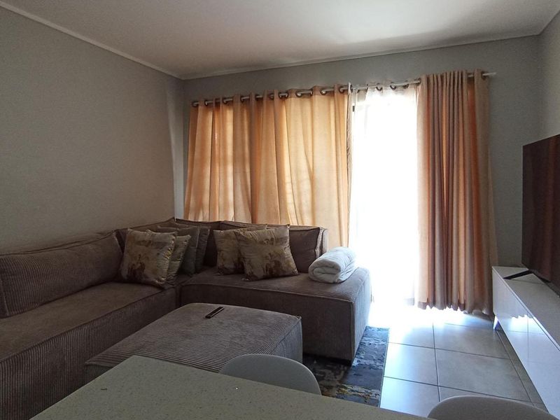 A comfortable living room featuring tiled flooring and a sliding glass door that provides access to the outdoor area.