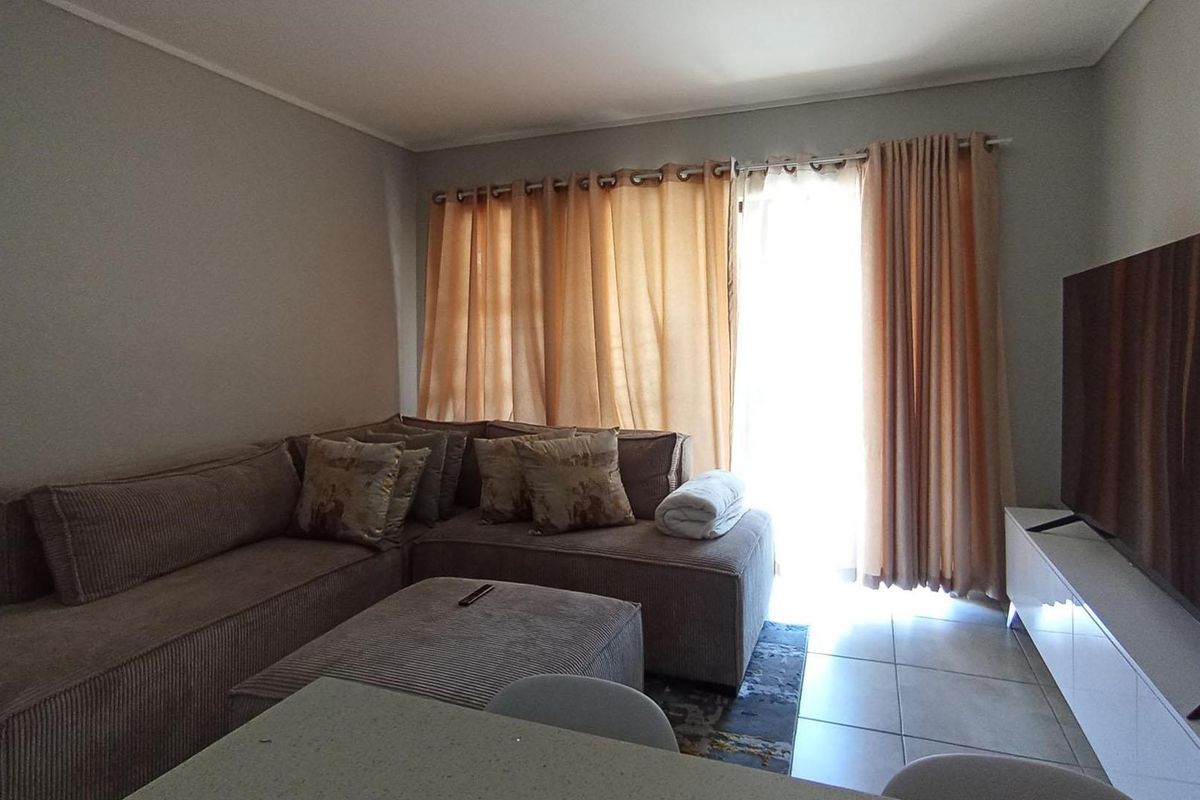 A comfortable living room featuring tiled flooring and a sliding glass door that provides access to the outdoor area.