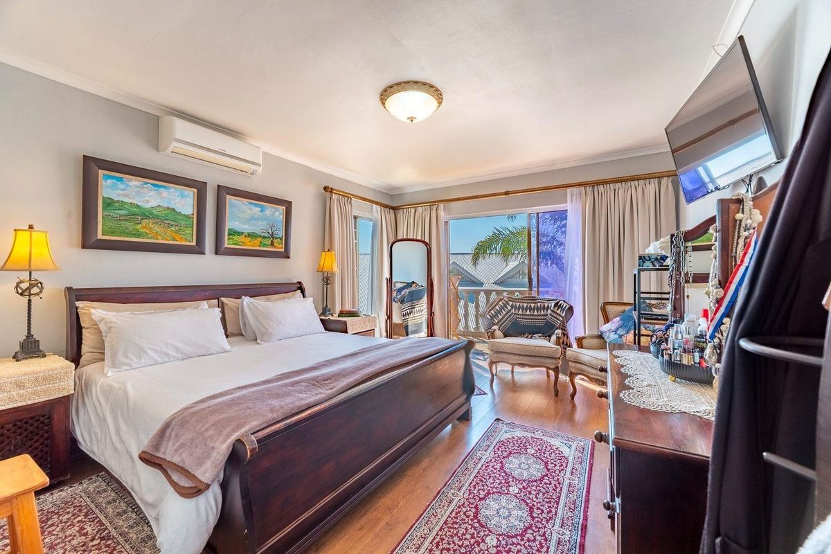 A well-maintained bedroom featuring hardwood flooring, a split-system air conditioner, and direct access to a private balcony through sliding glass doors.