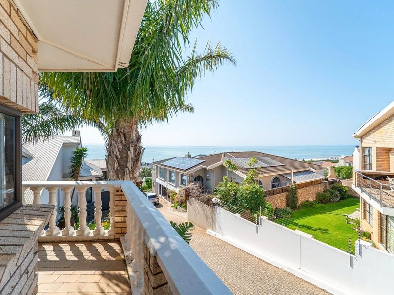 An elevated balcony featuring a classic balustrade, offering expansive views of the surrounding neighborhood and the ocean.