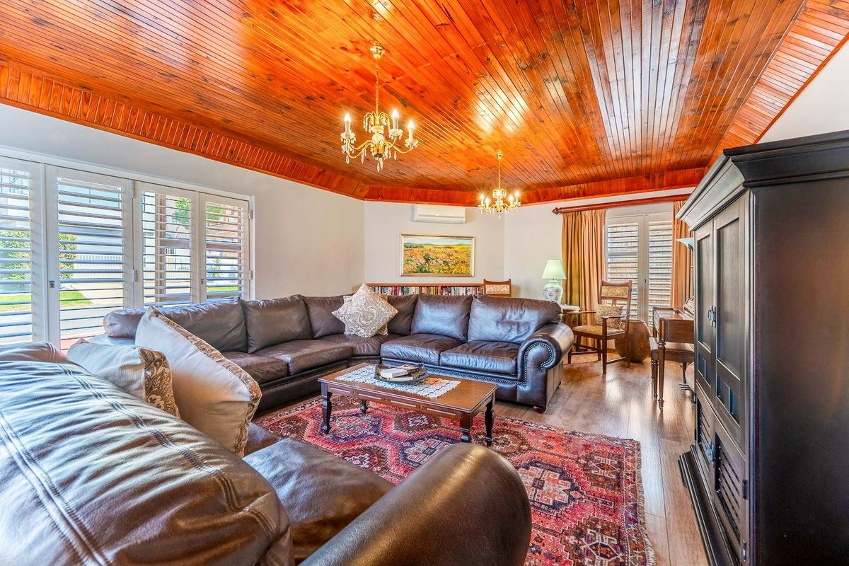 Spacious living room featuring a warm timber tongue and groove ceiling, plantation shutters, and split system air conditioning for year-round comfort.