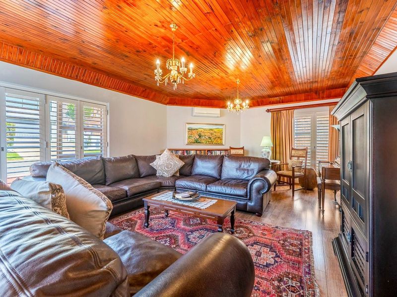Spacious living room featuring a warm timber tongue and groove ceiling, plantation shutters, and split system air conditioning for year-round comfort.