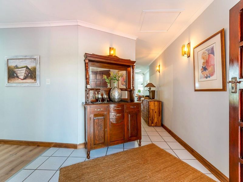 A welcoming entrance hall featuring tiled flooring, warm wall sconce lighting, and a solid timber door, leading into the main living areas of the home.