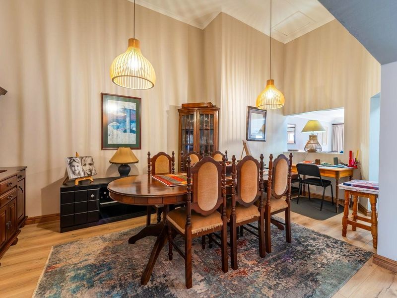 A spacious dining room featuring high vaulted ceilings, modern laminate flooring, and stylish pendant lighting, creating an inviting atmosphere for meals.