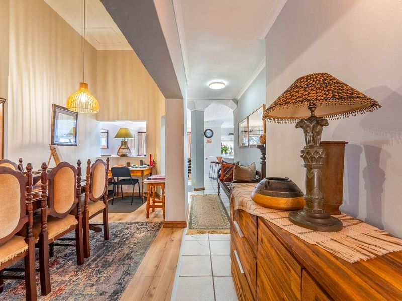 Open plan living and dining area featuring a mix of tiled and laminate flooring, connected by a central archway with integrated lighting.