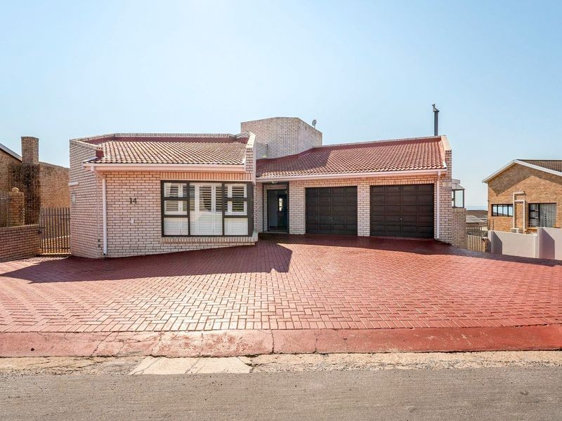 Front elevation of a brick house featuring a double garage, paved driveway, and security shutters on the windows.