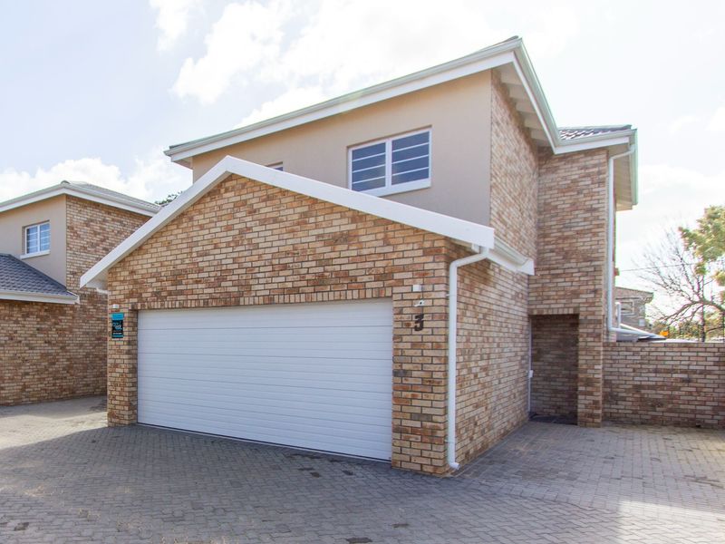 Front elevation of a double-story townhouse featuring a brick facade, paved driveway, and a secure double garage.